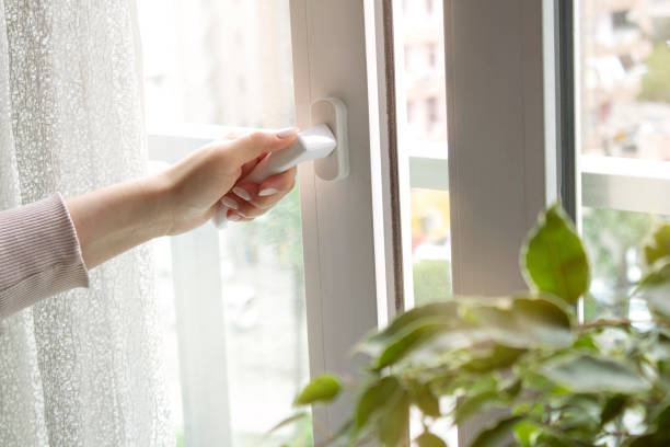 Woman's hand at home opening the white plastic window door. Room airing with fresh air. Ventilation concept.